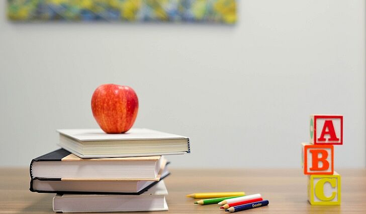 Bücher, Stifte und Buchstabenklötze auf dem Lehrertisch